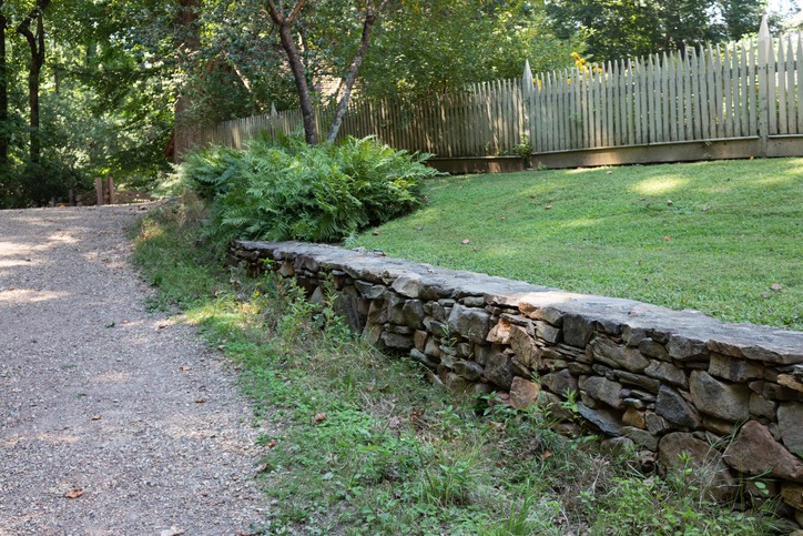 Natural fieldstone retaining wall alongside a gravel path