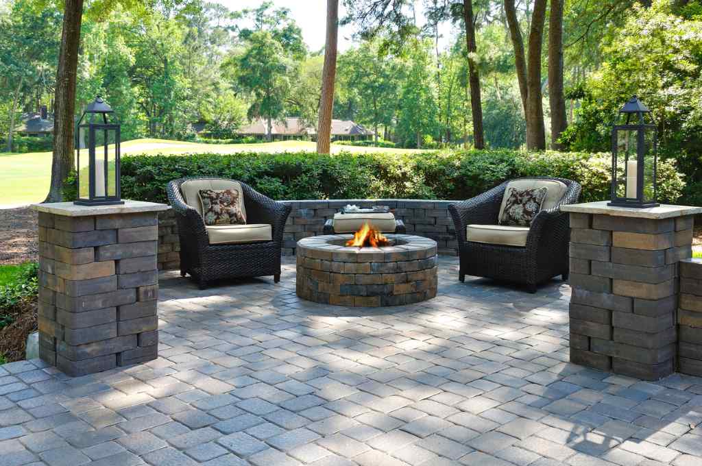 A beautiful outdoors paver patio with a fire pit and patio furniture