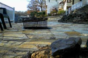 A flagstone patio with a stone firepit and grill at Lake of the Ozarks.