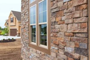 New house with earthtone stone veneer cladding.