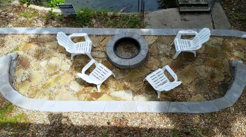 Patio made of Flagstone pavers set in wooded area with gravel filler.