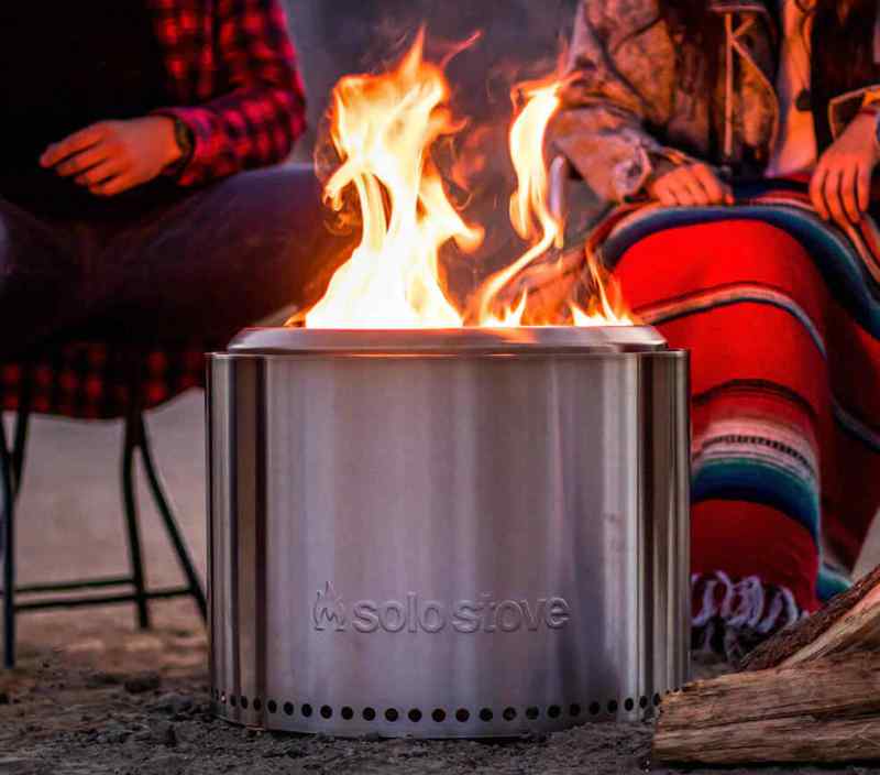 Solo Stove portable fire pit with a strong flame burning set between two campers