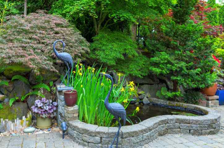 Colorful water feature made of stone pavers with surrounding ornamental trees and statuary