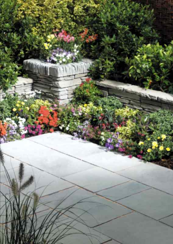 Elegant planters made of pavers at the end of a flower bed and garden wall