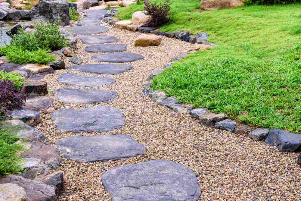 Image of a winding path of decorative landscape stone surrounded by bright green grass.