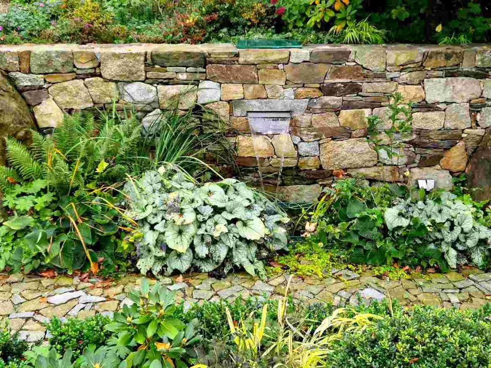 Stunning beige retaining wall stones complimented by various types of greenery.