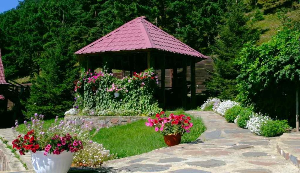 Rock and stone landscaped garden with a stone wlk, gazebo, and rock patio decorated with flowers .
