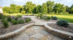 A professionally landscaped backyard in Columbia, MO featuring decorative river rock and a flagstone patio by Southwest Stone Supply.
